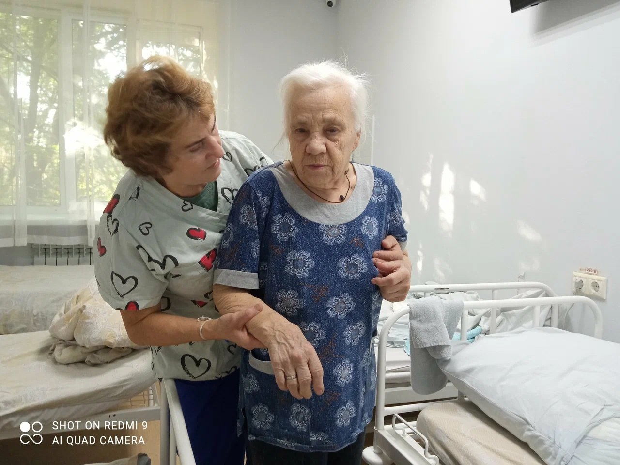 Сотрудник помогает пациентке передвигаться